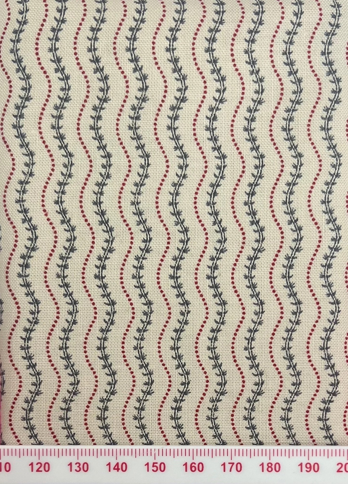Green vines between red squiggles on beige cotton